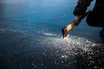 A man cuts ice with an ax in winter. Winter fishing