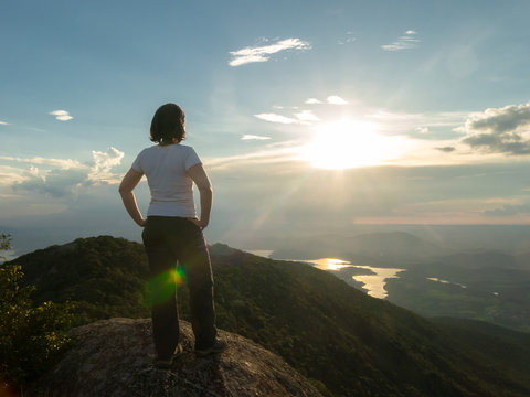 Unrecognized people - girl in mountain summit top looking landscape and dam reservoir - backlight sunset