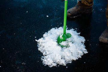 Fisherman drills a hole in the winter on the river. Winter fishing