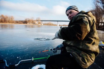 A man is fishing on the ice in the winter. Winter fishing