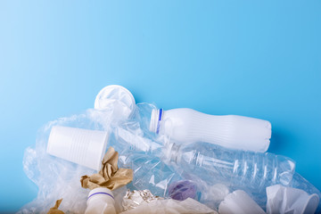 Unsorted clean garbage in a pile. Bottles, bags and paper on blue background. Environmental pollution and waste sorting