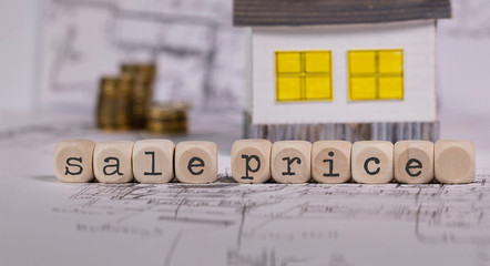 Words SALE PRICE composed of wooden letter. Small paper house in the background.