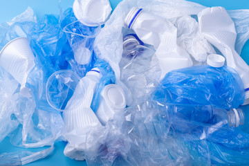 Used clean plastic garbage in a pile. Bottles and bags on blue background. Environmental pollution and waste sorting