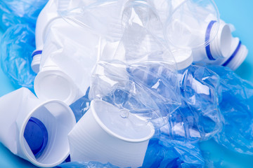 Used plastic garbage in a pile. Bottles and bags on blue background. Environmental pollution and waste sorting