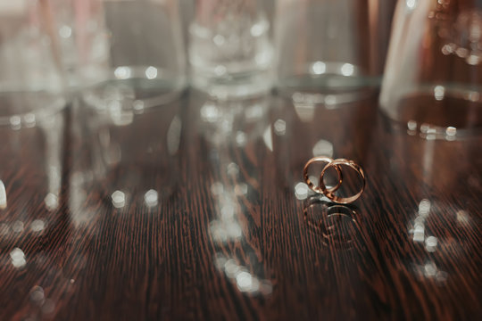 Wedding rings on dark surface shining with light close up macro. Water splashes. Reflection. Lights and smoke.