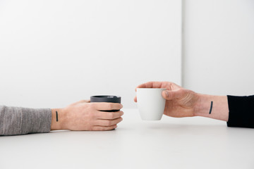 A couple with matching minimal tattoos holding a cup of coffee.