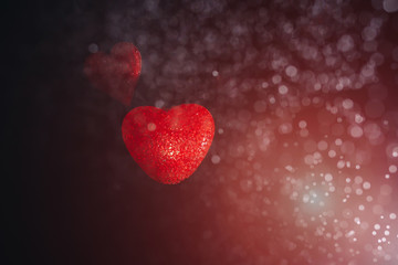 Fototapeta premium Two hearts are floating on a black background in the splash and the light. Valentine's day