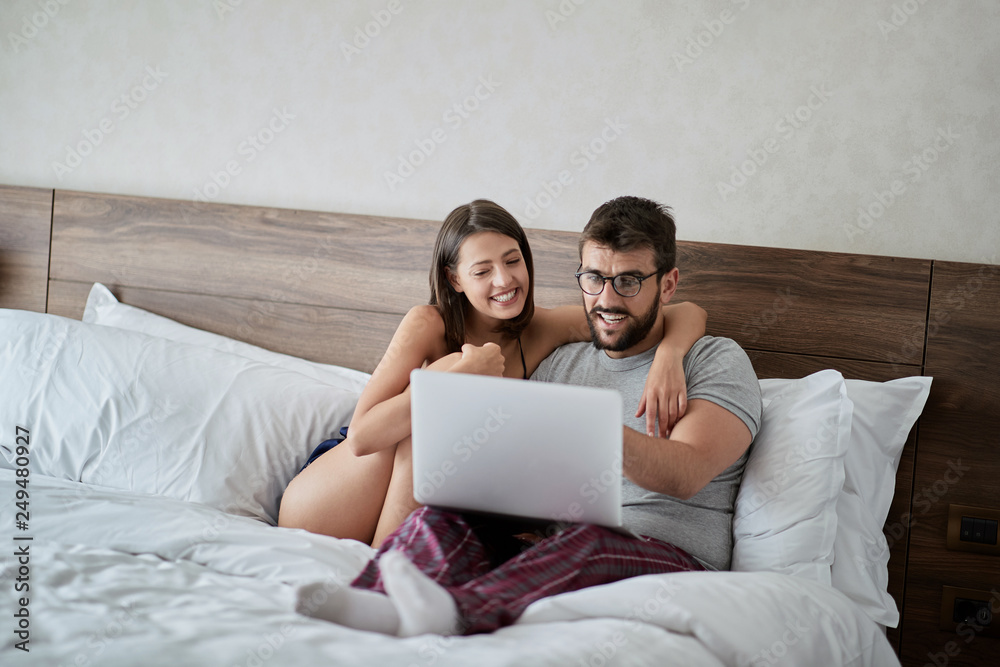 Wall mural couple in the bed with laptop and surfing on internet. Modern lifestyle concept..