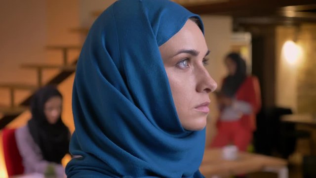 Closeup portrait of adult beautiful muslim businesswoman in blue hijab turning to camera and looking forward