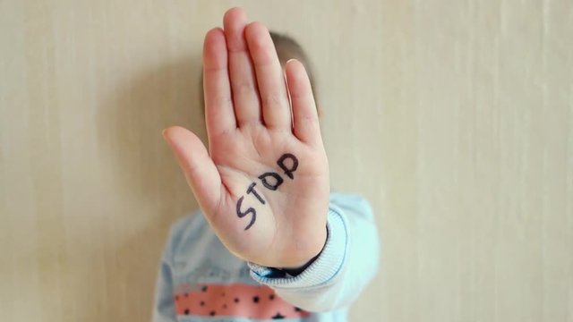 Concept of domestic violence and child abusement. A little girl shows her hand with the word STOP written on it. Children violence.