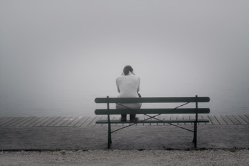 Traurige Frau  sitzt einsam auf der Bank und denkt nach - obrazy, fototapety, plakaty