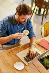 Male working at laptop and drinks coffee.