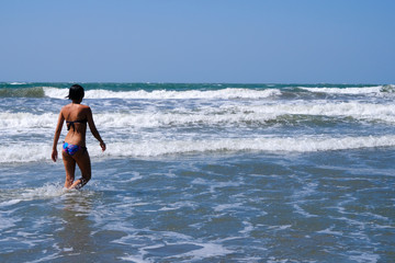 Fototapeta premium girl walks into the water on the beach