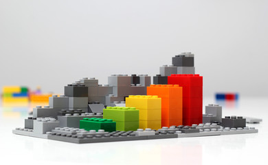 Progress chart made of bricks. Isometric composition of colourful toys on white table.