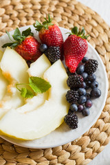 Fruit salad made from sliced melons and berries. Strawberries, blueberries, blackberries and mint leaves. Dietary fruit salad for breakfast, weight loss concept. Healthy snack.