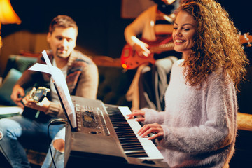 Woman playing clavier. Selective focus on woman. Home studio interior.