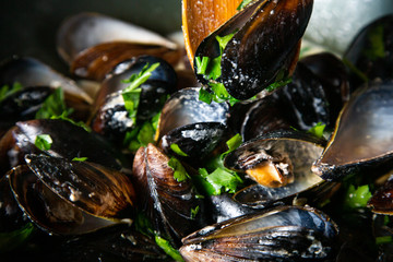 Mussels with parsley and garlic in wok pan on wooden table
