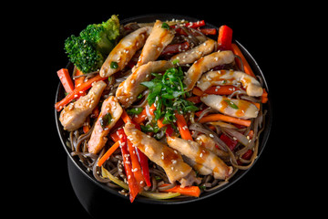 Soba Noodles (buckwheat) with chicken and vegetables: carrots, sweet peppers, broccoli on a black background. Sushi menu. Japanese food