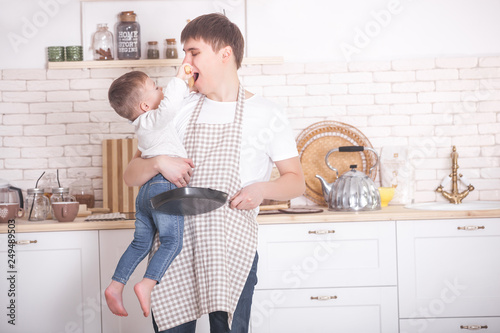 Young father cooking with his little son. Dad and child on the kitchen. Mothers day helpers. Man with kid making a dinner or breakfast for the mother.