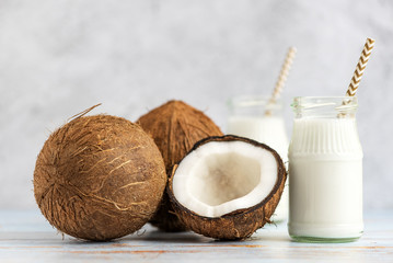 Coconut and jar of coconut milk on a light wooden background
