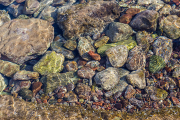 Colorful stones underwater in the sea with reflections of the sun