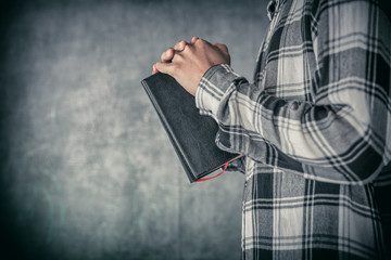 young man standing holding bible and praying. christian concept.