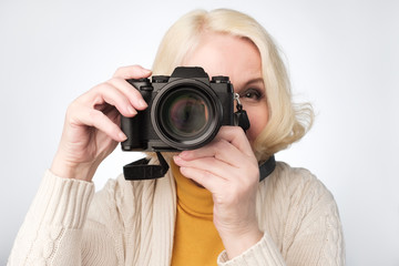 Senior blonde woman taking photo with camera