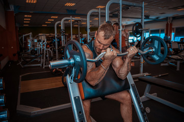 Naklejka na ściany i meble Sports man lifts weights in the gym.