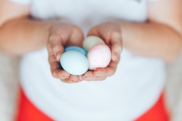 woman's hands holding colored pastel eggs eater