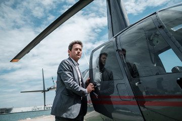 Businessman standing near private helicopter