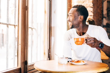 Fototapeta na wymiar Handsome african man drinking a coffee in establishment