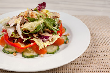 Vegetable salad with corn and mushrooms on a white plate on the table.