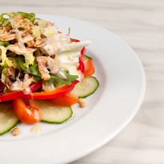 Vegetable salad with corn and mushrooms on a white plate on the table.