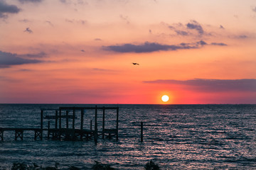 Sunrise or sunset over the sea. Sunrise clouds. Sun appeared from the horizon.Wooden pier.