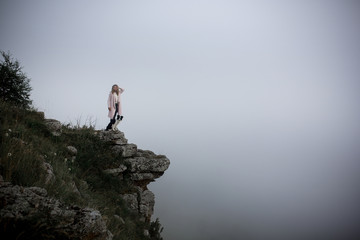 cool Girl and dog border collie on edge of rock in mountain in fog