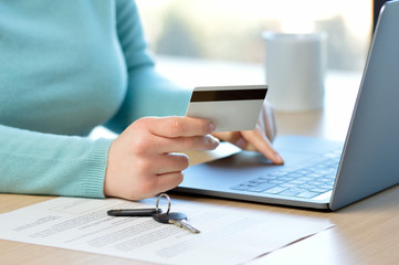 Cropped shot of a a woman hiring a home insurance on the internet with credit card at home