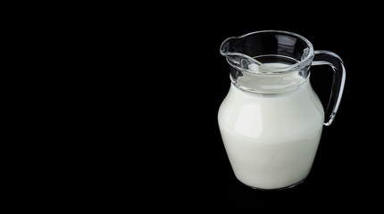 Glass jug of milk on black background with copy space