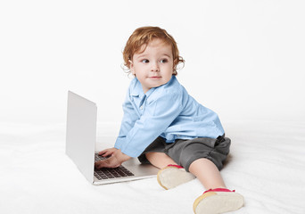 Cute baby boy typing on laptop keyboard