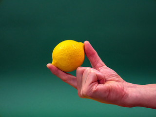 Lemon in hand on green background isolation