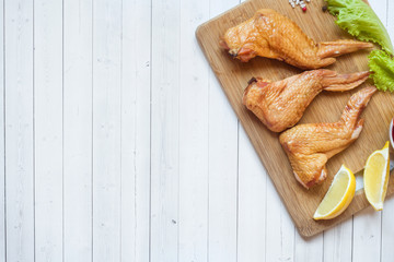 Smoked chicken wings with fresh lettuce tomato and lemon. Copy space