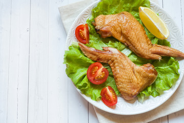Smoked chicken wings with fresh lettuce tomato and lemon. Copy space