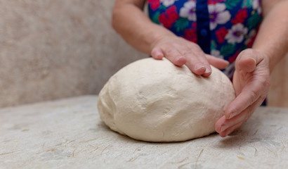 Woman kneads dough with hands in the kitchen