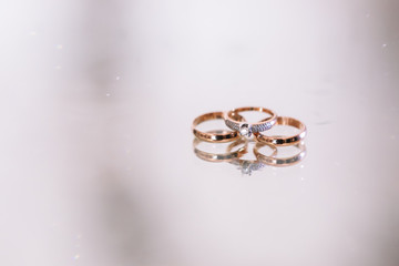 3 wedding gold rings on the white background glass with water drops . Wedding. Diamonds.
