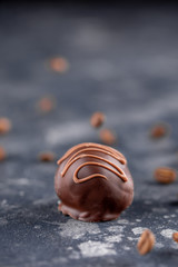 Set of luxury chocolate candies with coffee filling decorated with caramel splashes. Exclusive handmade bonbons on wooden background. Close-up.