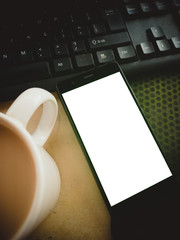 cup of coffee on laptop with white screen on smartphone
