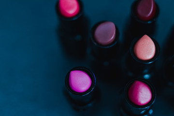 group of red pink and nude lipsticks with different colors and textures on dark table