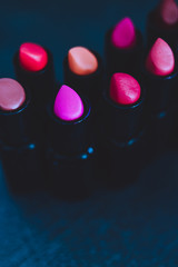 group of red pink and nude lipsticks with different colors and textures on dark table