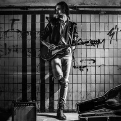 A street musician playing on guitar in the underpass. Vagrant lifestyle. Playing in the underpass to make a living. Unemployed musician. Future rock star.