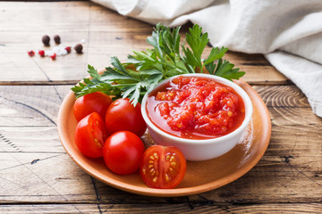Tomato sauce pasta in a bowl and fresh tomatoes with parsley on a wooden table