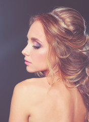 Naklejka premium Beautiful woman with curly long hair on dark background .